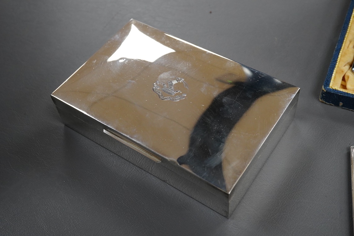 A modern silver mounted rectangular cigarette box, London, 1985, with engraved crest and motto, 15.5cm, together with a silver cigarette case, a George V pierced silver sugar basket with blue glass liner, a cased set of
